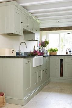 a kitchen filled with lots of green cabinets and counter top space next to a window