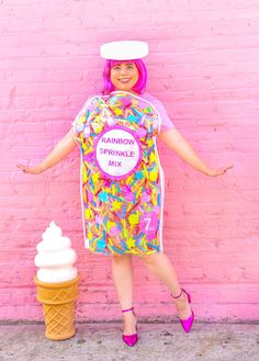 a woman standing in front of a pink wall with an ice cream cone on her head