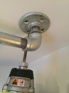 a close up of a metal object on the ceiling above a fire extinguisher