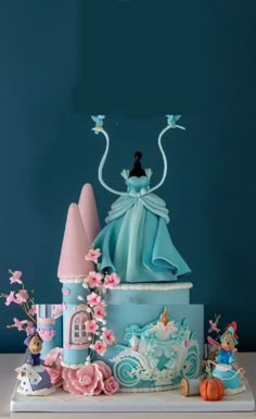 there is a blue cake with princess figures on it