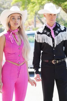 a man and woman dressed in western style clothing standing next to each other on the street