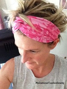 a woman with a pink headband is blow drying her hair