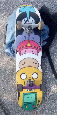 a skateboard with cartoon characters on it sitting next to a person's jeans