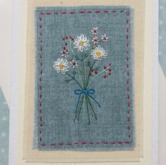 an embroidered card with daisies on it