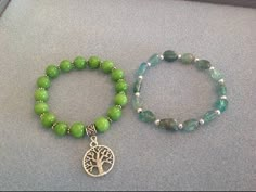 two bracelets one with a tree charm and the other with a green bead