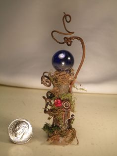 a blue glass ball sitting on top of a metal stand next to a dime coin