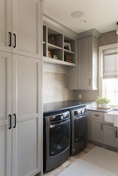 a washer and dryer in a small room with cabinets on either side of the window