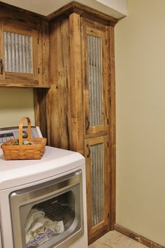 a washer and dryer in a small room with wooden cabinets on the wall