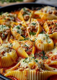 a pan filled with shells covered in sauce and cheese