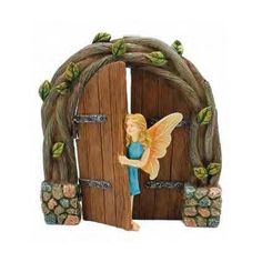 a fairy figurine standing in front of a wooden door