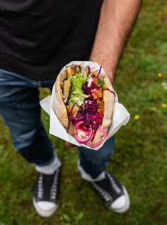 a man holding a taco filled with lots of veggies