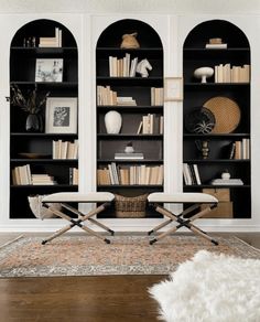 a living room filled with furniture and bookshelves next to a rug on top of a hard wood floor