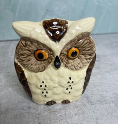 a ceramic owl figurine sitting on top of a gray surface with orange eyes