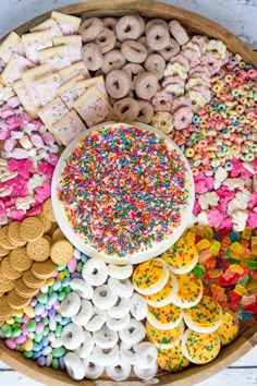 a wooden platter filled with lots of different types of donuts and sprinkles