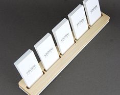 four white business cards are placed on a wooden stand with three smaller ones in the middle