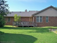 a brown brick house sitting on top of a lush green field