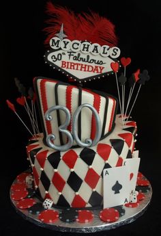 a birthday cake decorated with red and black checkered designs, playing cards, and the number thirty