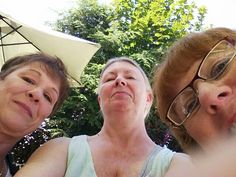 three women are posing for the camera under an umbrella