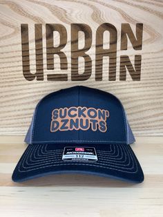 This stylish Suckon Dznuts Hat is the perfect addition to your fashion accessories collection. Made of a comfortable blend of cotton and polyester, this hat features a snapback fit and an on-trend baseball cap design, making it a must-have for any fashion-forward individual. Unisex Design: This hat is perfect for both men and women. Durable Material: Made with high-quality cotton-polyester blend that ensures long-lasting durability. Care Instructions: To keep your hat looking its best, we recommend hand washing it. Available in a wide range of colors! Patches are permanently affixed with adhesive using a hat press with a very high temperature. Flat Bill Hat, Baseball Cap Design, Flat Bill Hats, Dec 8, Accessories Collection, Cap Design, Fashion Flats, Trucker Cap, Unisex Design