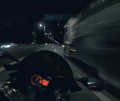 a motorcycle driving down a street at night