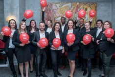 a group of people holding red balloons in front of a painting