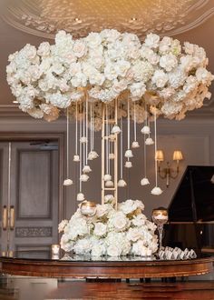 a grand piano is adorned with white flowers and chandelier hanging from the ceiling