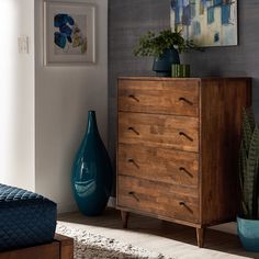 a wooden dresser sitting next to a blue vase