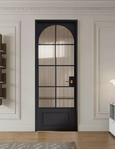 an empty room with a black door and shelves on the wall, next to a rug