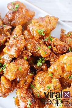 a white plate topped with chicken wings covered in sauce and garnished with parsley