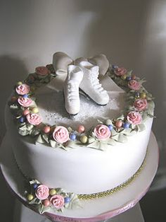 a white cake decorated with pink roses and ice skates