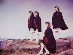 three women dressed in black and white standing on rocks