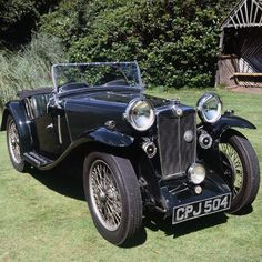 an old fashioned car parked in the grass