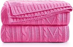 pink knitted blanket folded on top of each other in front of a white background