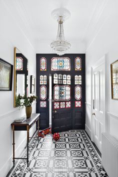 a black door with stained glass windows in a hallway next to a table and bench