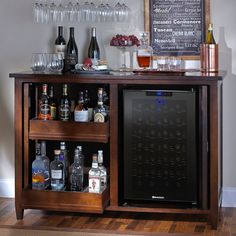 a wooden bar with wine glasses and liquor bottles on the top shelf next to it