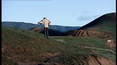 a man walking up a hill carrying a skateboard