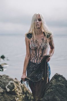 a woman standing on top of a rock next to the ocean