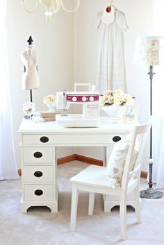 a white desk and chair in a room with a chandelier hanging from the ceiling