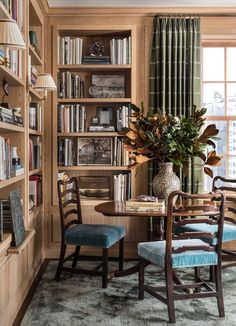 a dining room table with two chairs and bookshelves