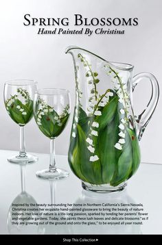 a glass pitcher and two wine glasses with flowers in them on a white table top