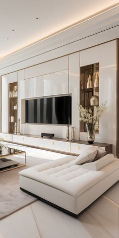 a living room with white furniture and a flat screen tv mounted on the wall above it