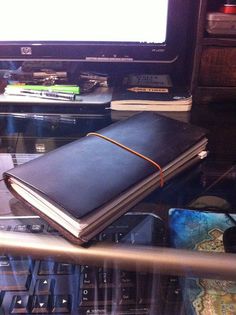 an open book sitting on top of a desk next to a computer monitor and keyboard