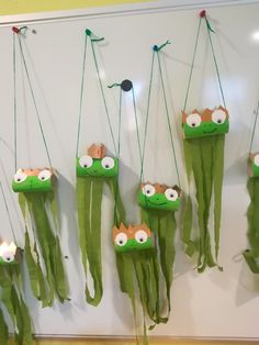 some very cute little green items hanging on the side of a white wall with eyes