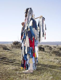 a man standing in the middle of a field with clothes hanging from it's back