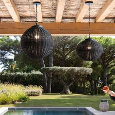 an outdoor pool with two hanging lights above it