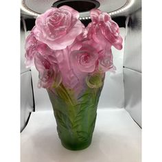 a vase with pink flowers in it sitting on a white tableclothed surface next to a mirror