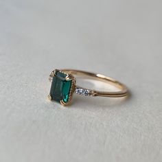 an emerald and diamond ring on a white surface