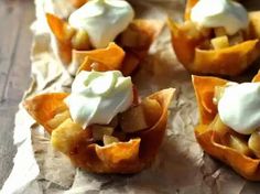 small desserts with fruit and whipped cream on top are sitting on wax paper, ready to be eaten