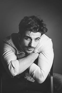 a black and white photo of a man leaning on a chair