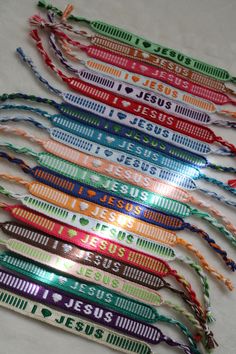 a bunch of colorful lanyards that are on a white tablecloth with the name jesus printed on them